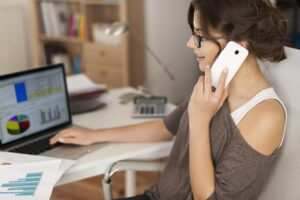 Girl on cell phone in front of computer at home