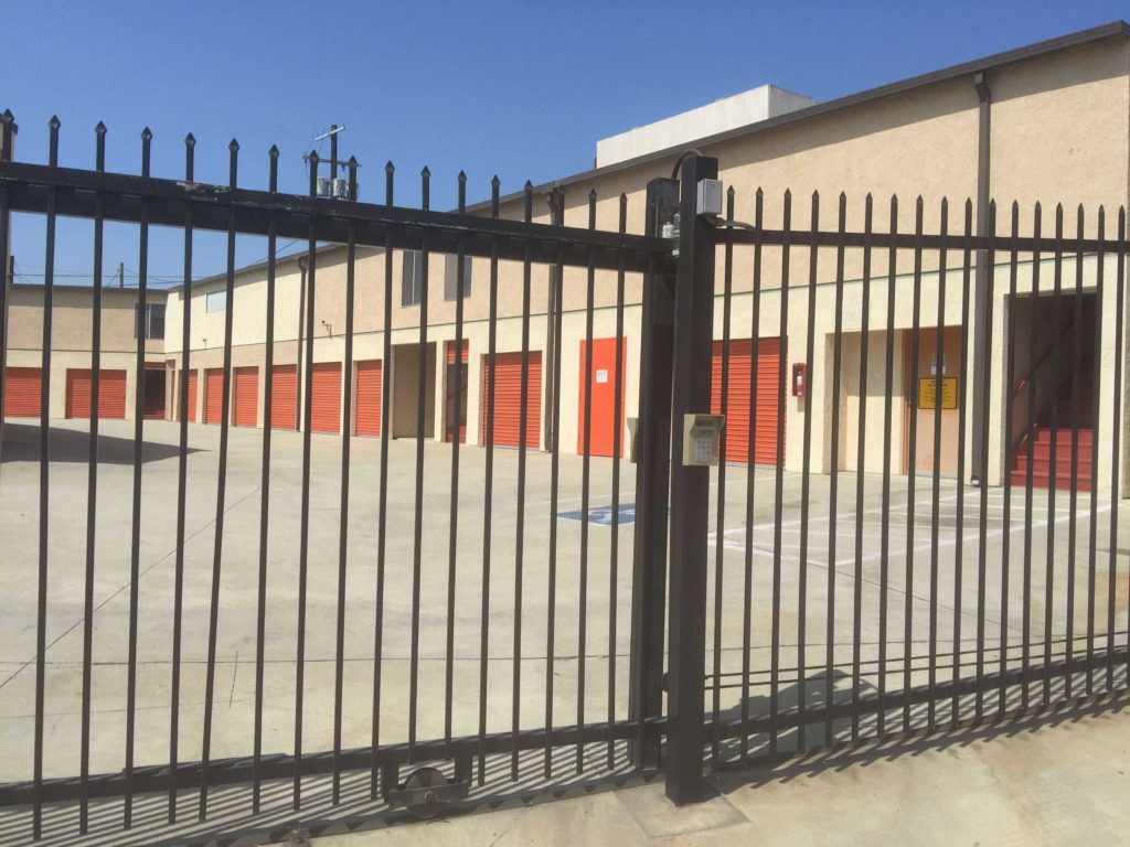 View of gate going into an area of outdoor storage units with orange doors