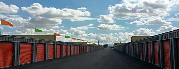 A long street view of outdoor storage units with red doors in a clean area