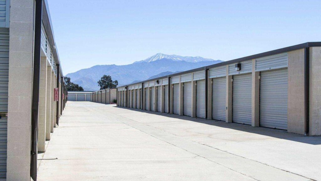 A long row of large outdoor storage units with white doors in a clean, open area