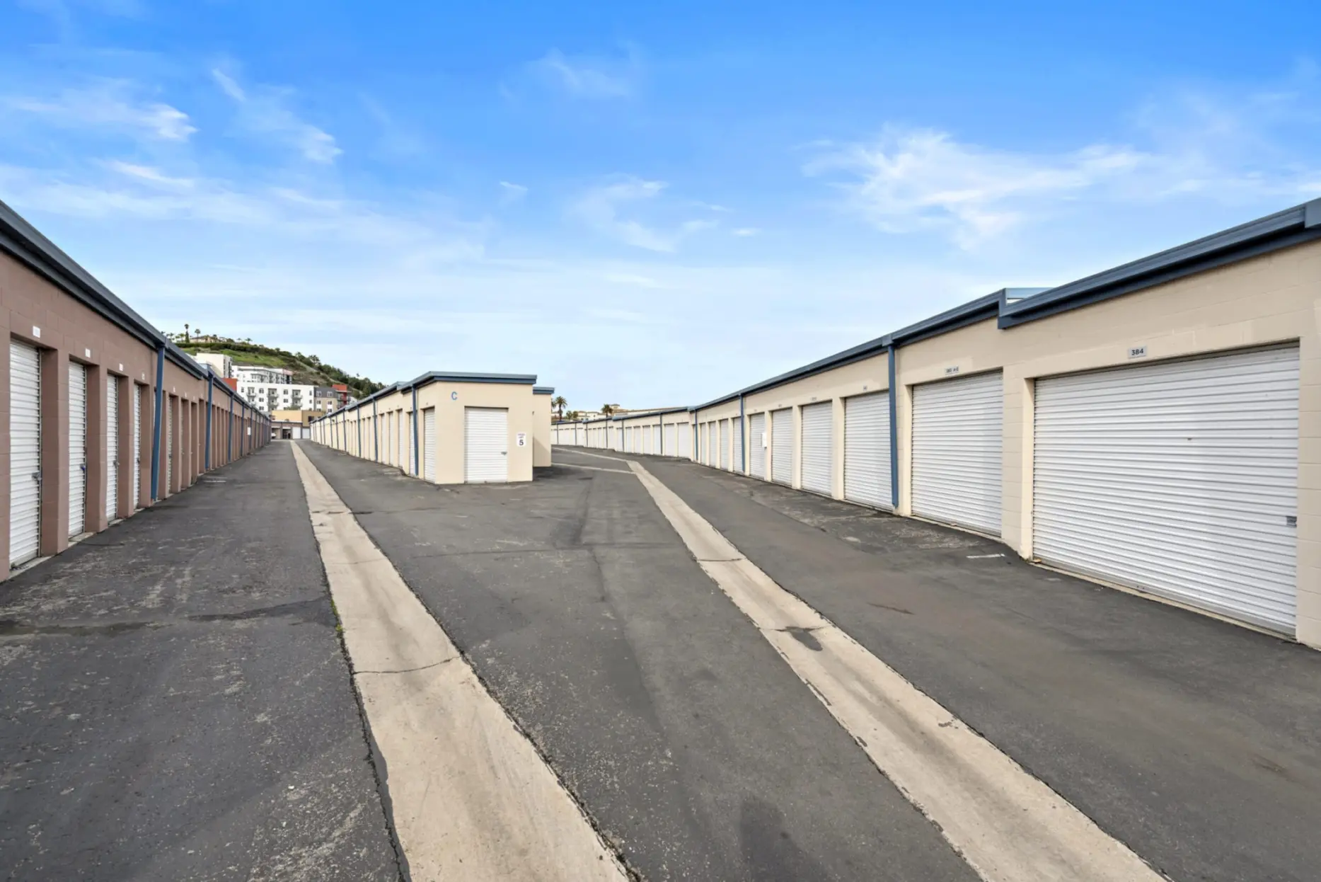 Rows of secured storage unit gates separated by a driveway at the Allsize Self Storage facility.
